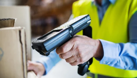 A warehouse worker uses a handheld barcode scanner.