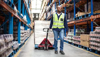 A food warehouse employee wheels pallets of goods.