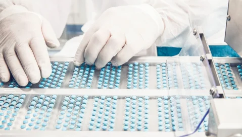 Worker inspecting pills in packaging