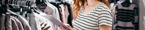 Woman taking clothing store inventory on tablet