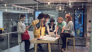 People huddled around a computer having a meeting.