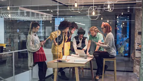 People huddled around a computer having a meeting.