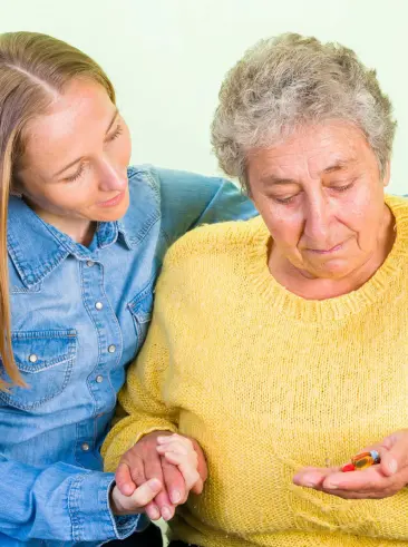 Helper with elderly woman taking her medication.