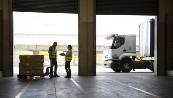 Warehouse workers at loading dock with palette of boxes