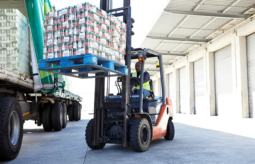 A forklift truck that lifts crates of tinned tomatoes onto a truck