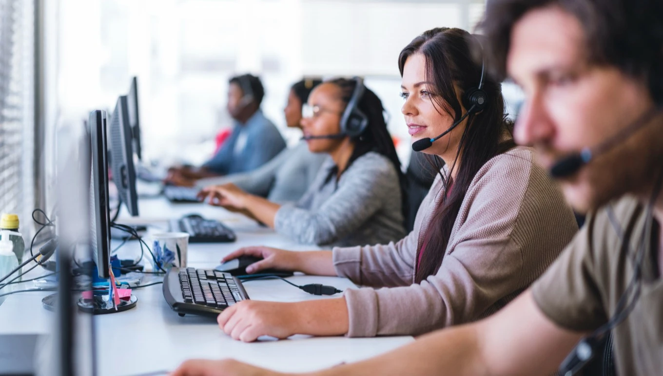 Workers in headsets using desktop computers