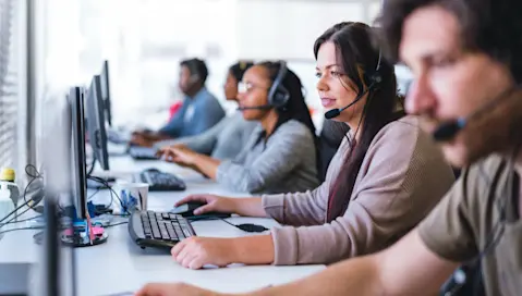 Workers in headsets using desktop computers