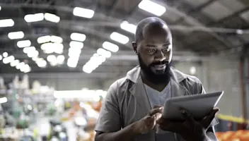 Male worker using tablet while standing in manufacturing industry.