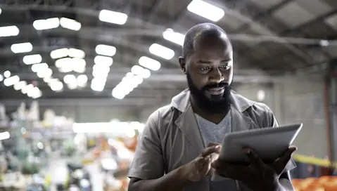 Male worker using tablet while standing in manufacturing industry.