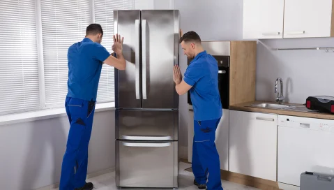 Two men pushing a refrigerator into place