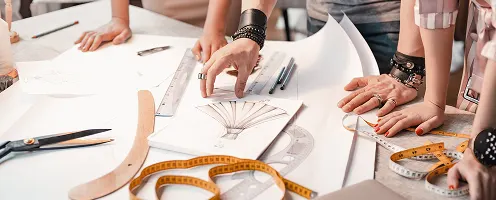 People stood around a table looking at product drawing to create a new product.