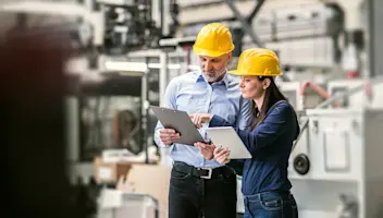 two people wearing hardhats in a factory 