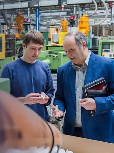 Workers looking at plastic parts in factory.