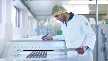 A food facility worker observes a conveyer line.