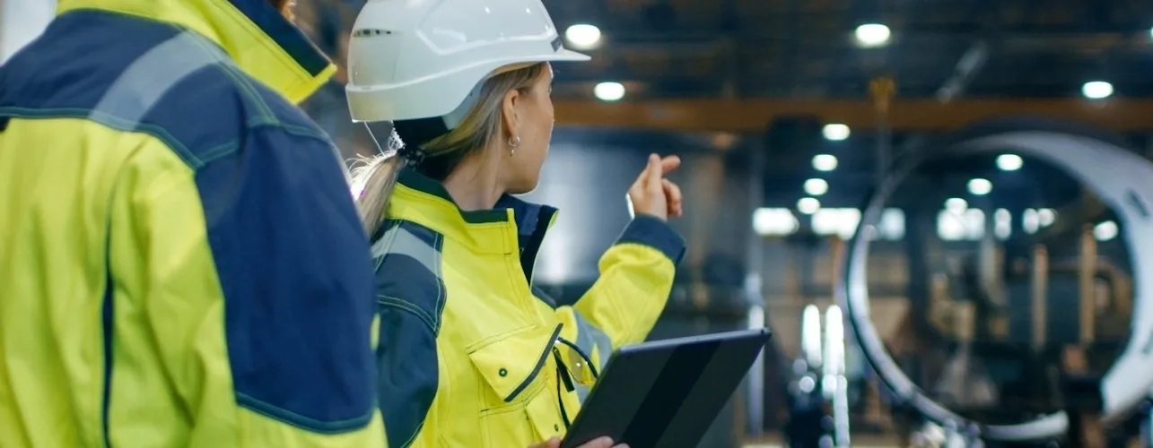 Des ingénieurs industriels, hommes et femmes, portant des casques de chantier et des gilets de sécurité.