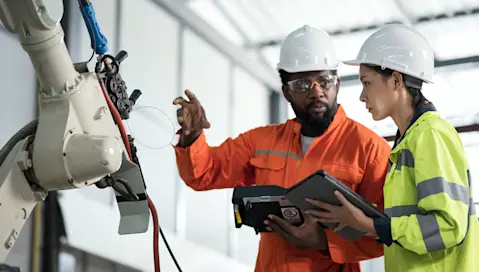 Shop floor workers reviewing equipment in factory