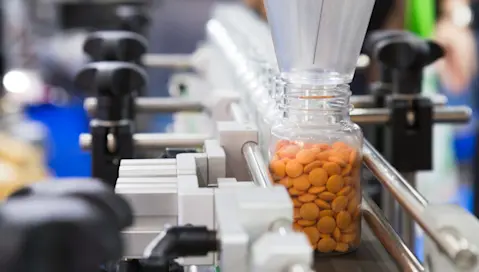 Bottle filled with pills on factory conveyor belt
