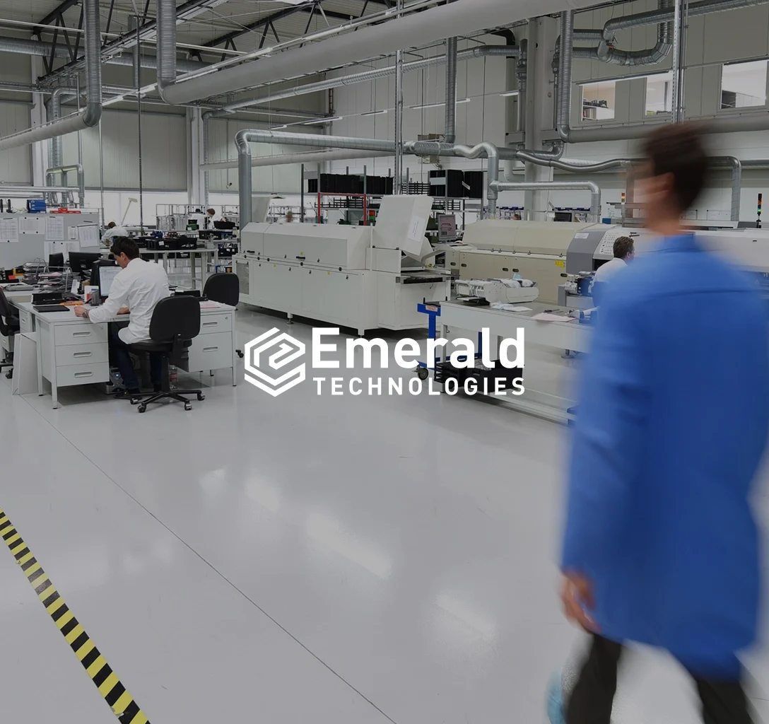 The Emerald Technologies logo against a backdrop of a manufacturing and design hall.