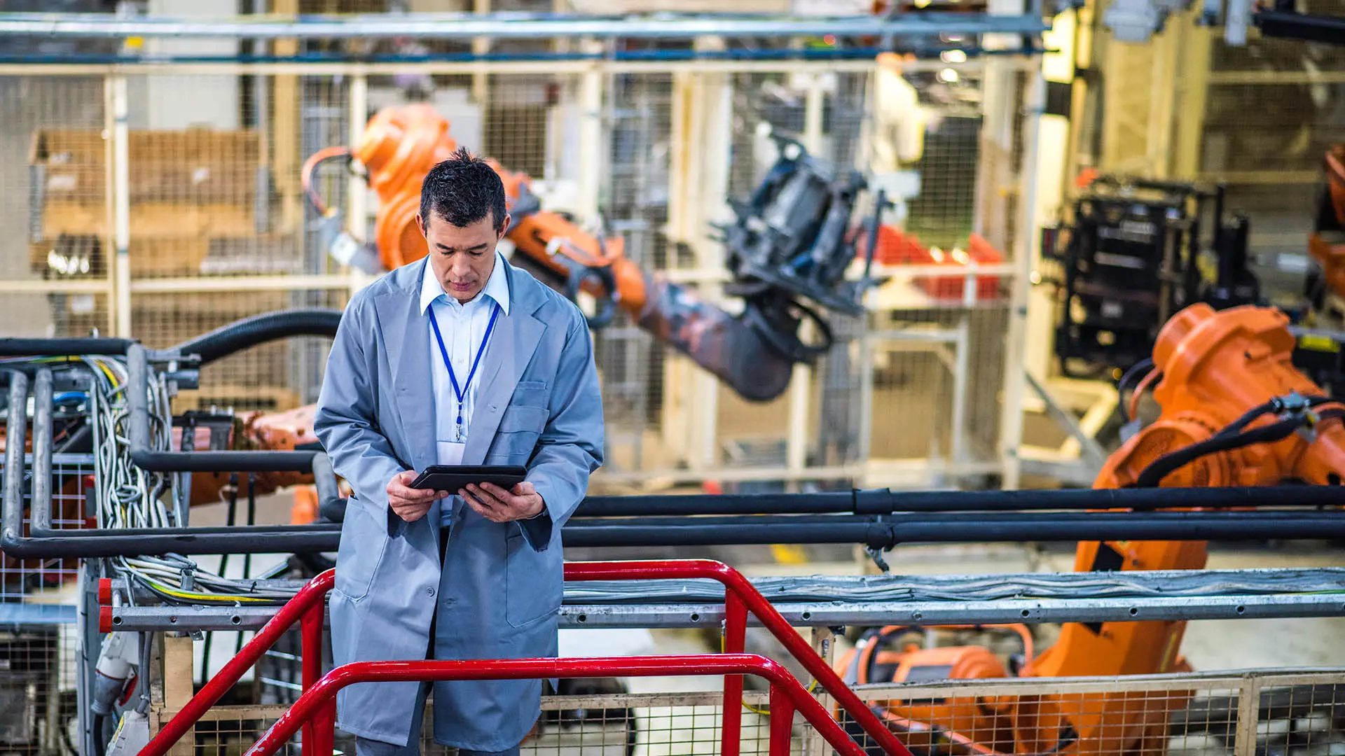Mann in einer Automatisierungsfabrik mit Blick auf ein Tablet.