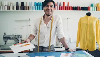 Young happy male designer working at fashion design table.