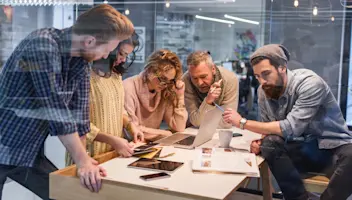 Product designers gather around a table and their materials.