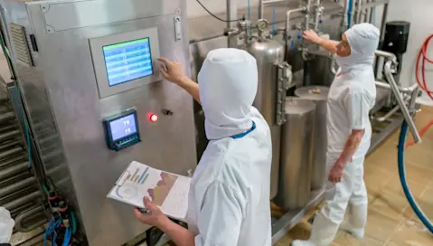 Food facility workers monitor machinery.
