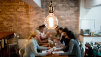 A lightbulb shines over a group of collaborators.