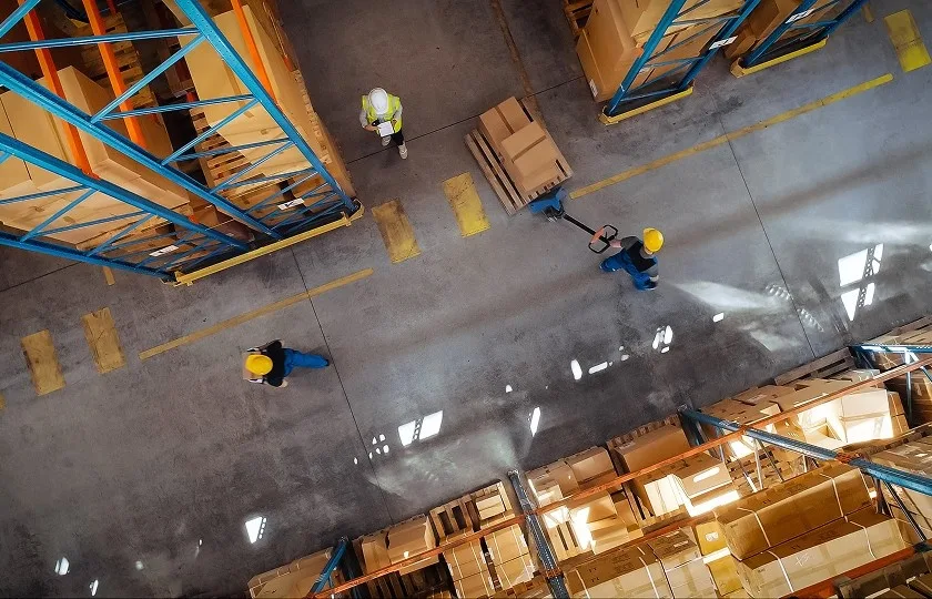 Forklift operator lifting pallets and boxes in a logistics distribution centre