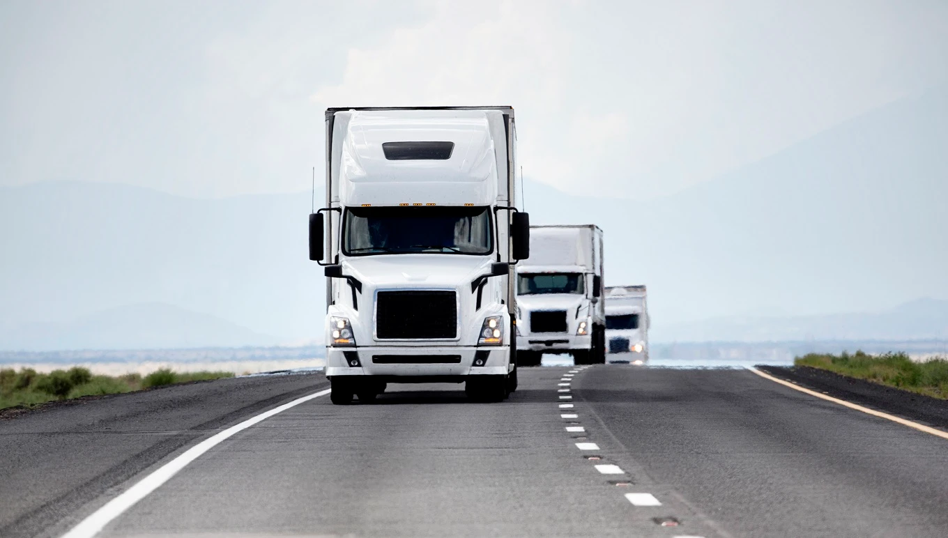 Fleet of trucks driving down a highway.