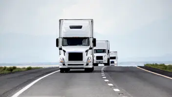 Fleet of trucks driving down a highway.