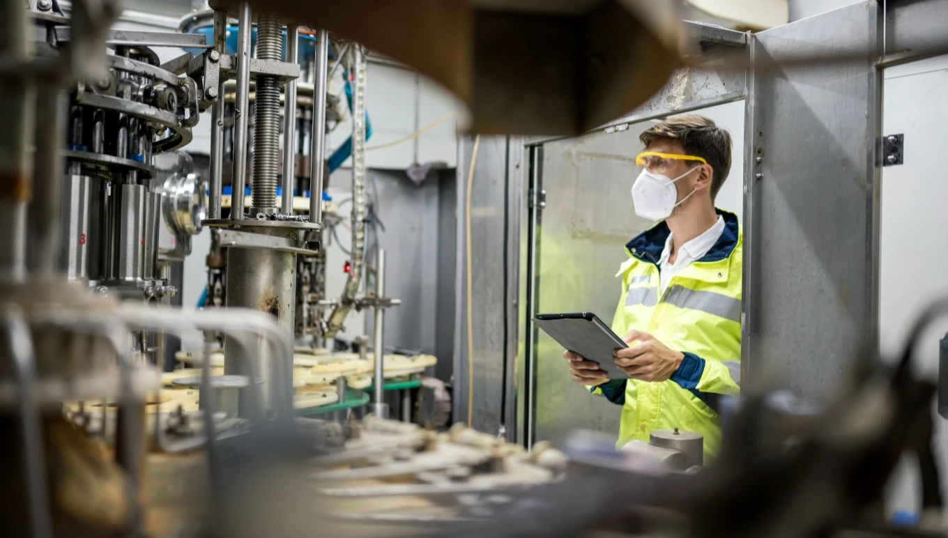 A food factory worker monitors manufacturing equipment in motion.