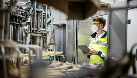 A food factory worker monitors manufacturing equipment in motion.