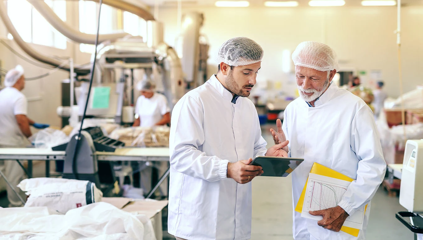 Two factory workers looking on a tablet