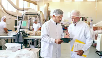 Two factory workers looking on a tablet