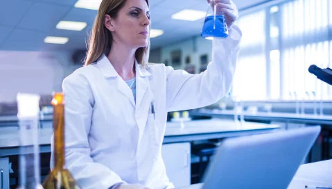 Scientist in lab looking at beaker