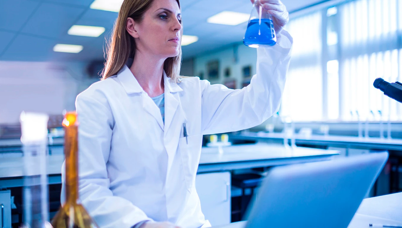 Scientist in lab looking at beaker