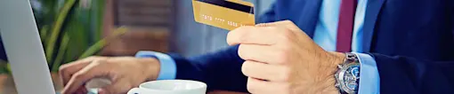 Online ordering on laptop with credit card in hand