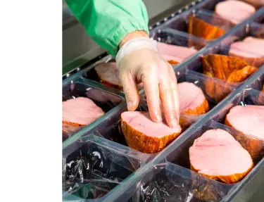 In einer Lebensmittelfabrik werden Fleischprodukte für die Verpackung bearbeitet.
