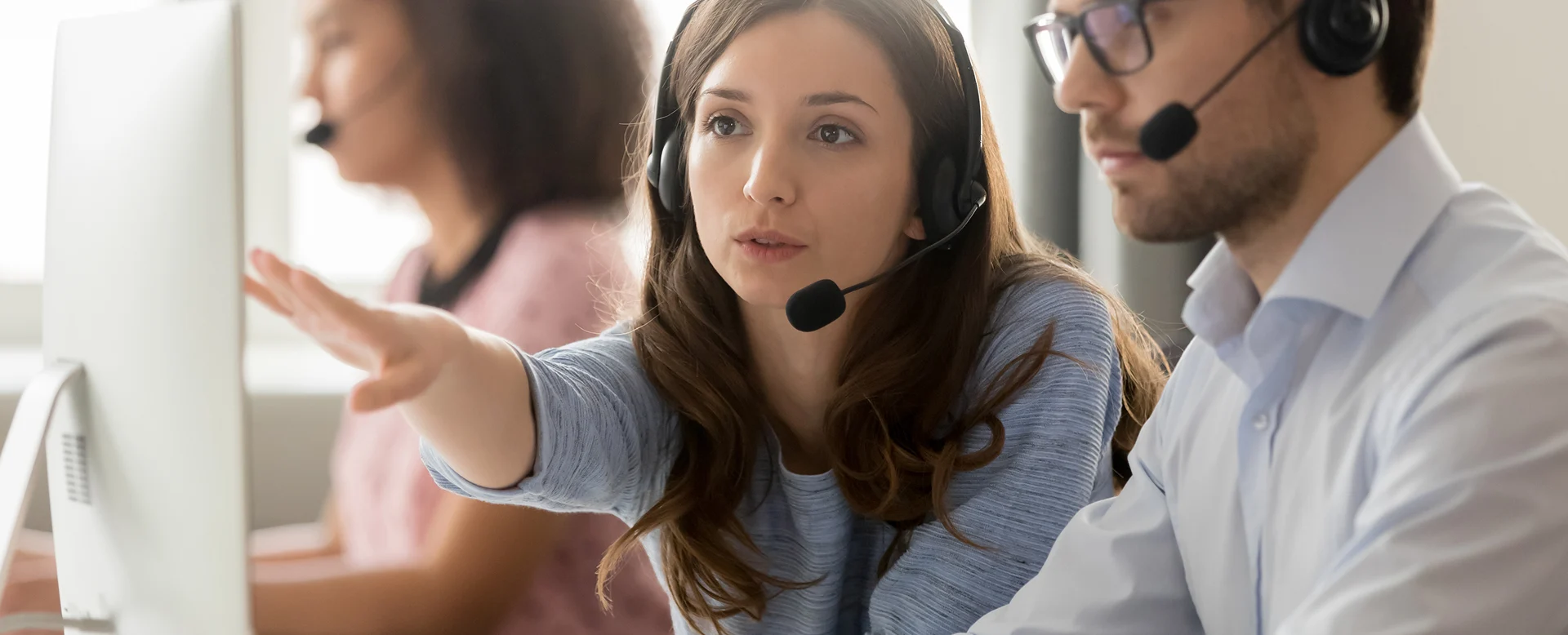 Call centre worker helping a new employee at a customer support desk