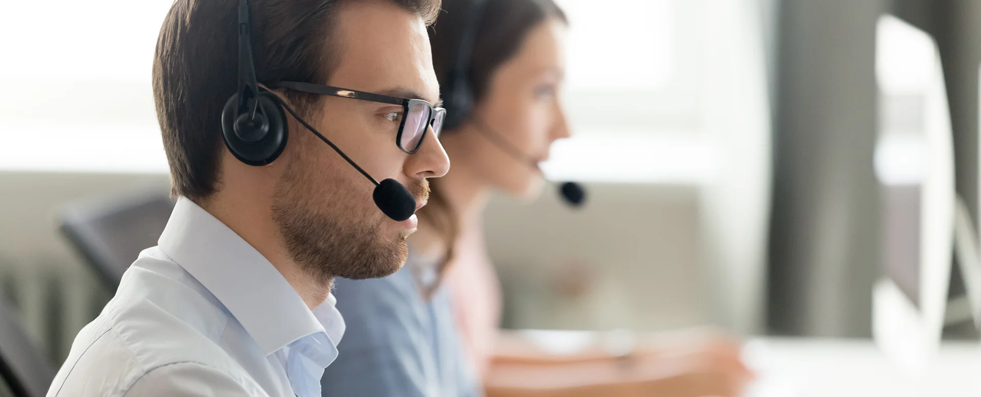 Call center operator agent in headset with microphone consulting client online close up