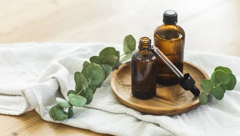 Amber glass bottles with essential oils and eucalyptus leaves on towel