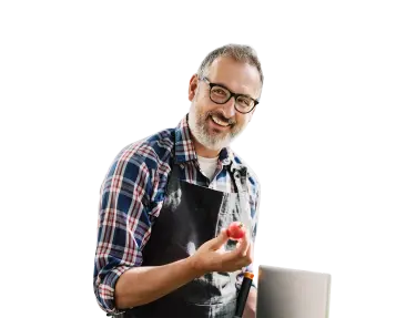 Un hombre sonriendo con un tomate en la mano.