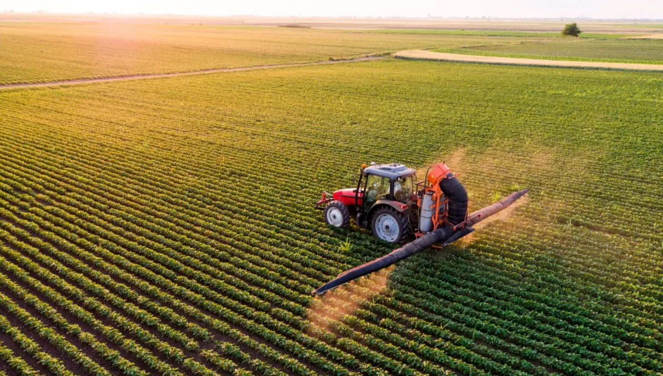 A farmer drives a tractor across a field.
