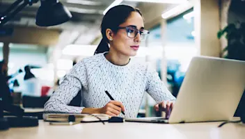 Serious professional business woman noting information from networks.