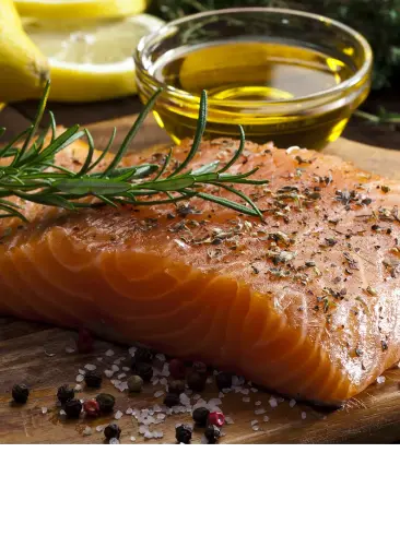 Salmon sliced on cutting board with lemon, oil and seasonings
