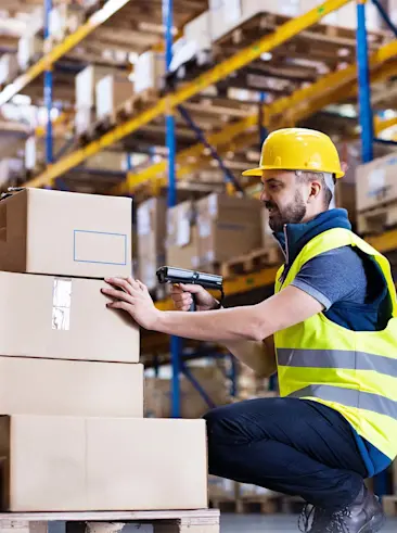 Warehouse worker RF scanning pallet of boxes.