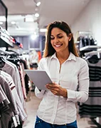 Woman in clothing store holding a tablet.