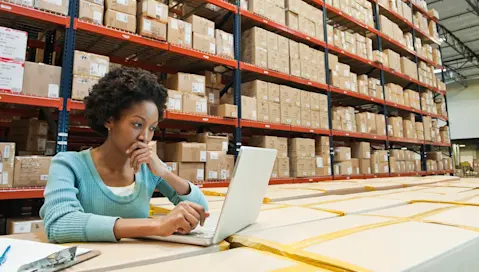 Women reviewing laptop in warehouse