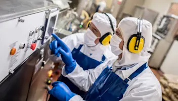 Food facility workers operate heavy production machinery.