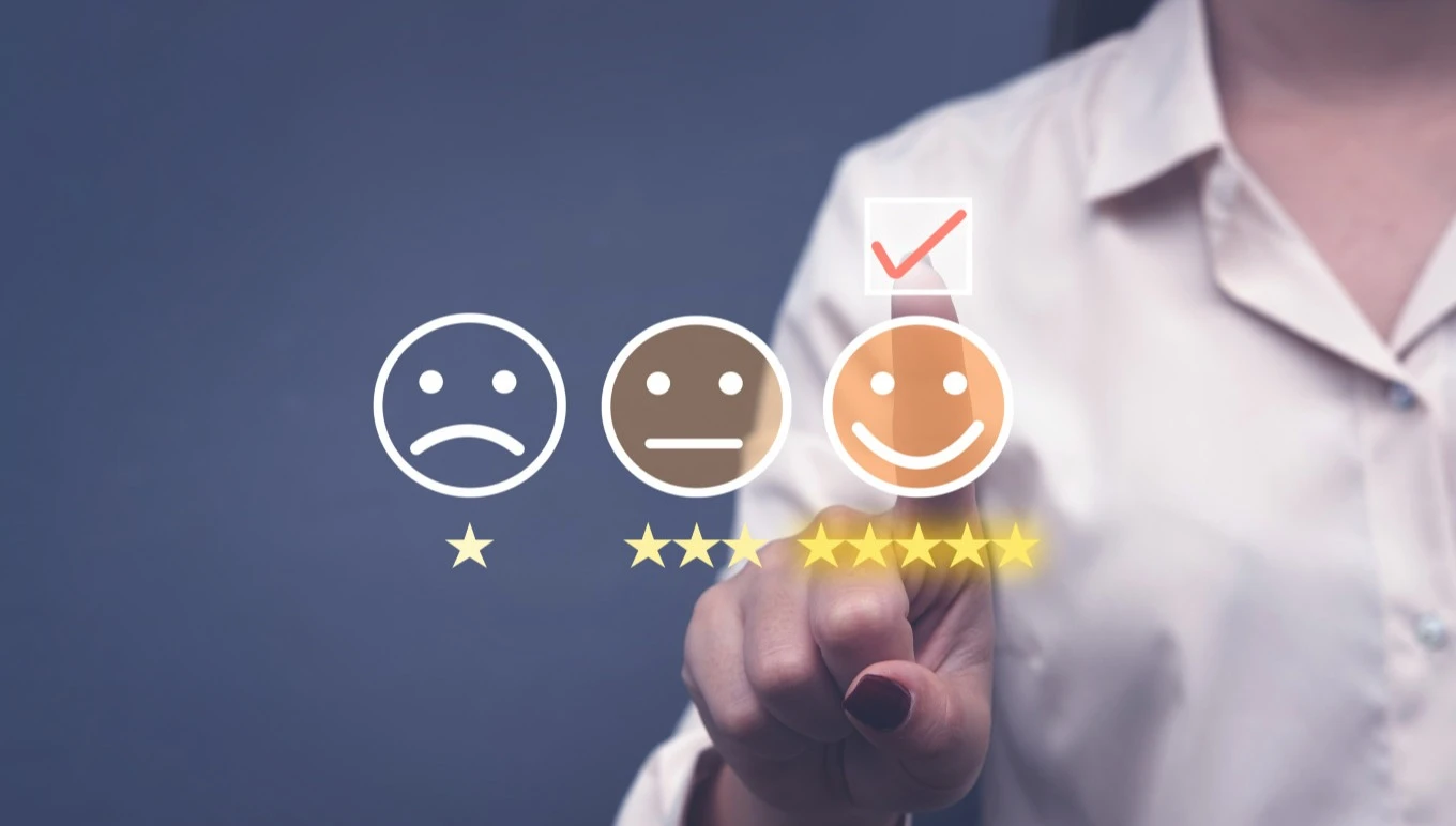 Three faces showing sad, neutral and happy expressions with a person pointing to the happy face
